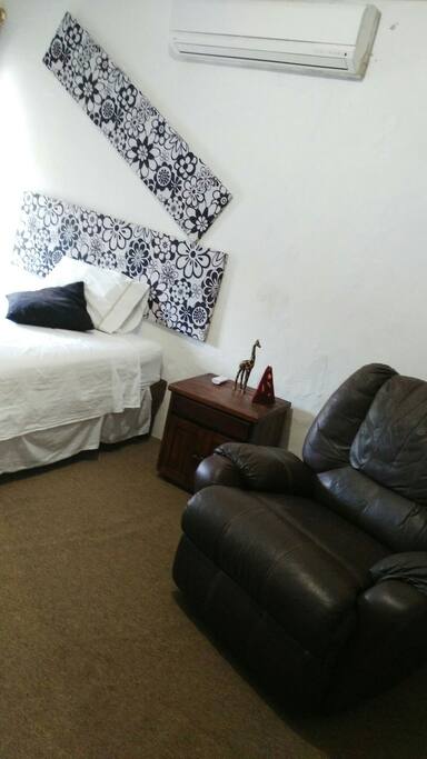 La cama matrimonial con un confortable sillón reclinable para su completo descanso y la recámara con una ventana con vista al exterior