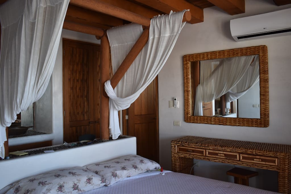 Master Bedroom with dresser and master bathroom, plus large picture windows with screens to listen to the ocean and access to the balcony.