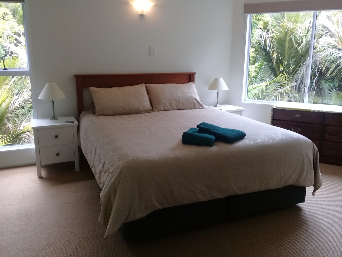 Двойна спалня с двойно легло, двоен гардероб и страничен прозорец с изглед към местната растителност.  Обърнете внимание, че калъфката на завивката може да се различава от снимката според наличността.  Лампите до леглото са сменени. Има мрежа против мухи за прозореца.