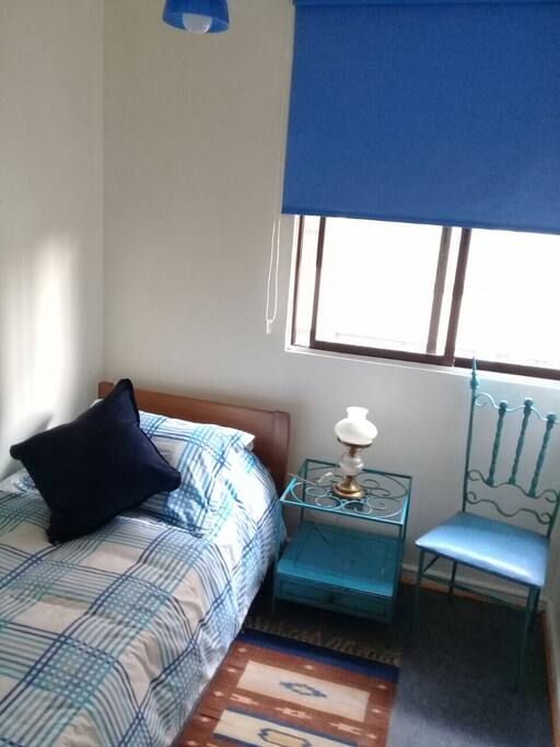 Dormitorio con cama, velador, silla, closet, espejo.
