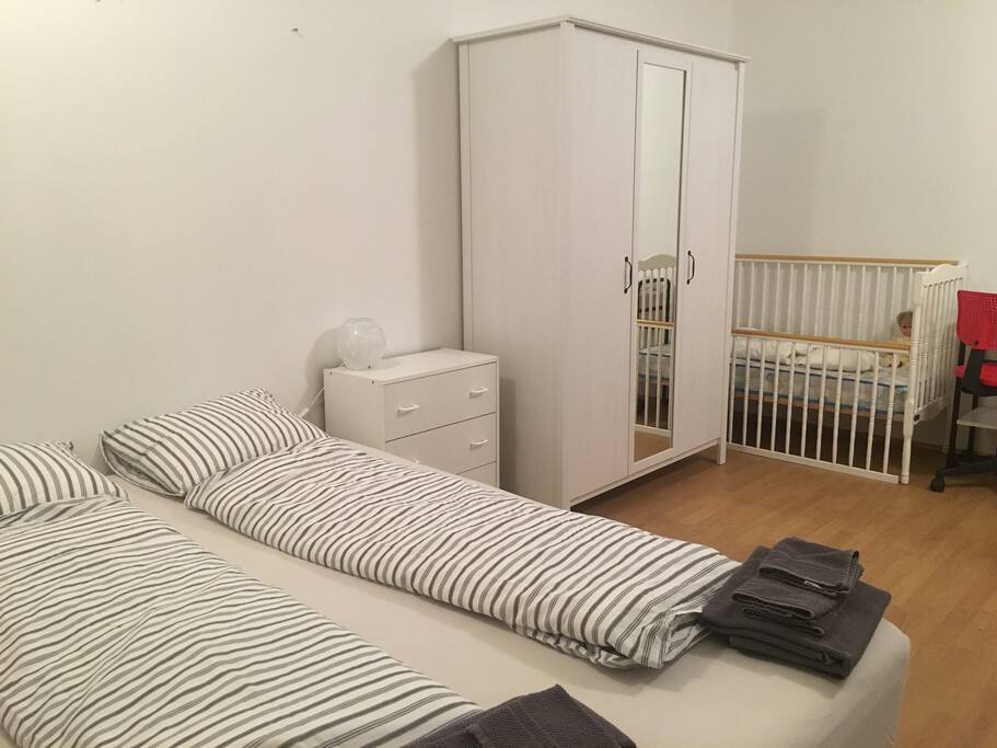 Bedroom with one double bed, one single bed and baby bed