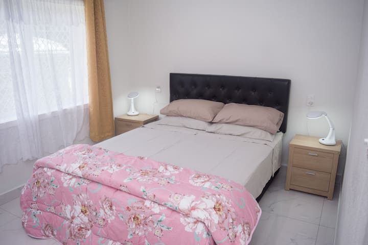 CHUMBA CHA KULALA 2. 

Kitanda cha foleni na meza za pembeni na taa vinasimama. Chumba kinafaa kikiwa na madirisha ya skrini ya usalama kwa usalama zaidi