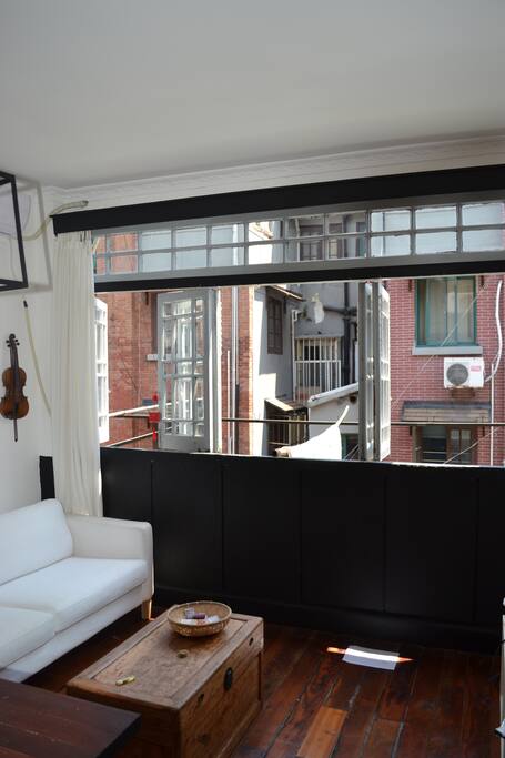 Living room with a large bay window on the 1st floor over looking an old traditional Shanghaiese street (no buildings, only two-three storeys Shanghaiese lane houses)