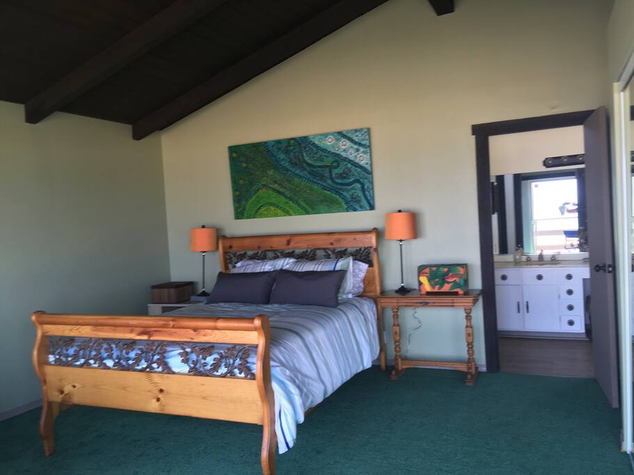 Queen size bed in the master bedroom and the door leading to the vanity and full bathroom.