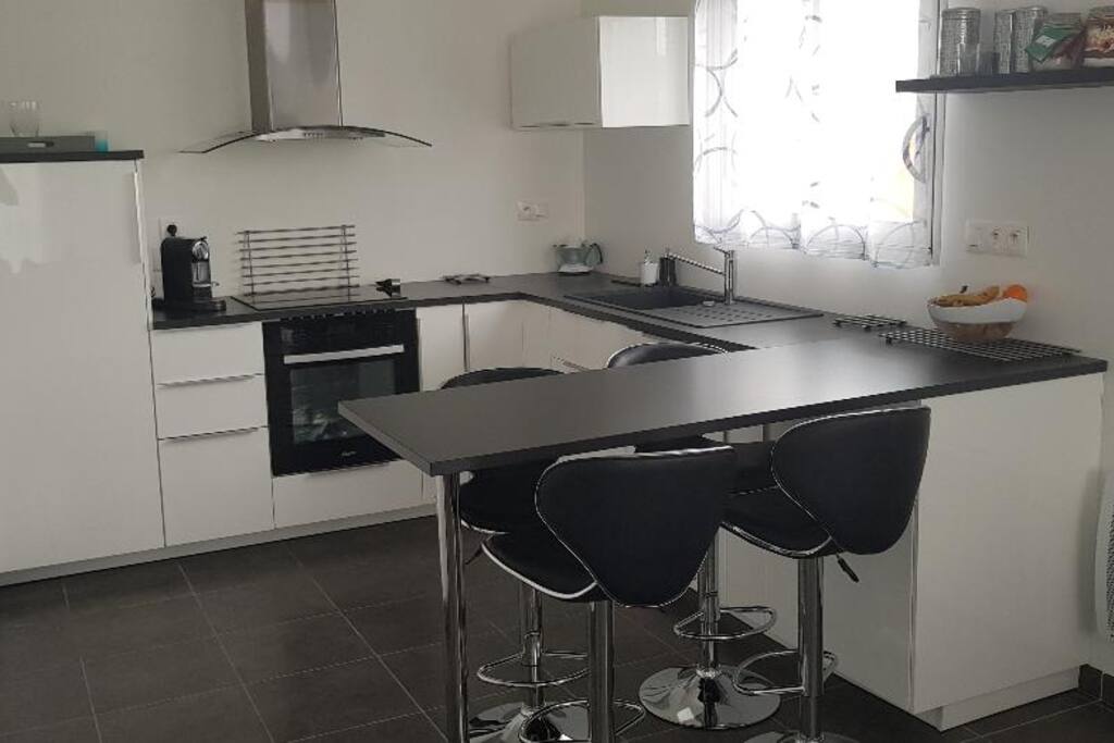 Cuisine ouverte avec frigo, four, plaques à induction, cafetière, presse-agrumes électrique et lave-vaisselle. Cellier attenant avec congélateur à tiroirs et lave-linge.