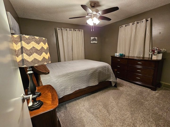 Glavna spavaća soba s bračnim krevetom (160 – 179 cm) onako kako se vidi s vrata spavaće sobe. Tu su komoda, ormar s vješalicama i stalak za prtljagu. 