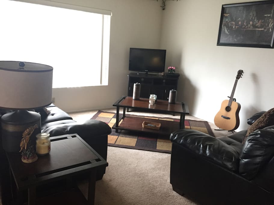 Living Room, with 2 leather couches, television, and large coffee table.