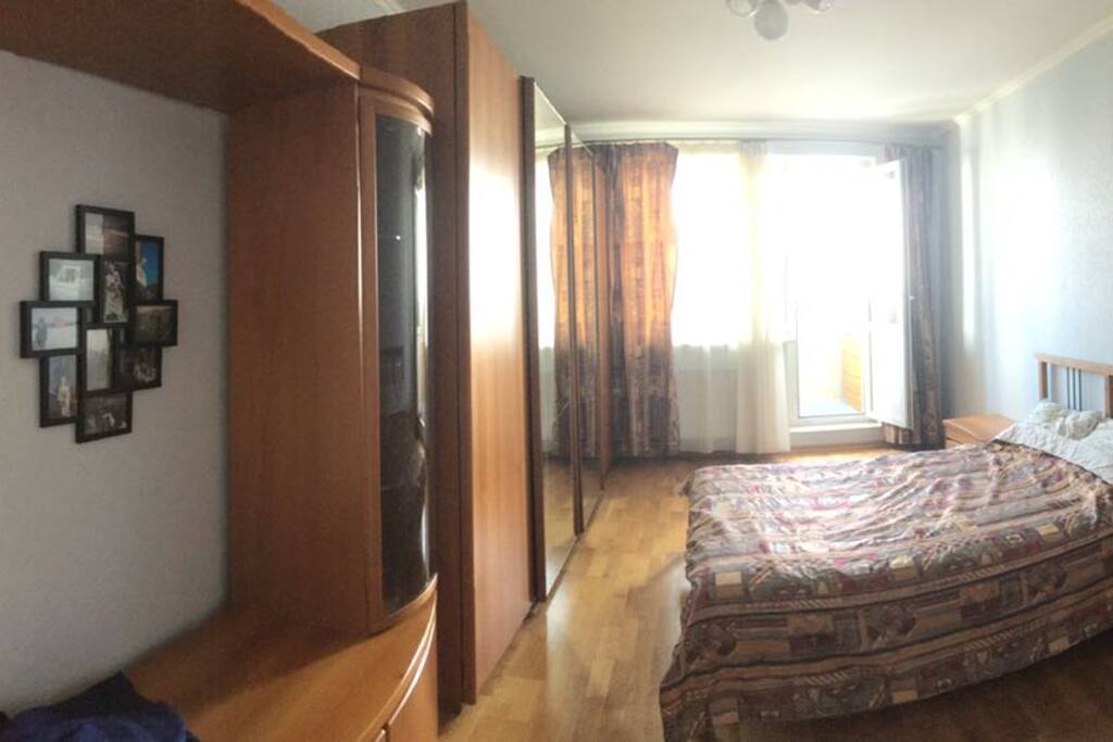 A giant bedroom with plenty of mirrors ;) a two-person bed, hardwood floor and a balcony