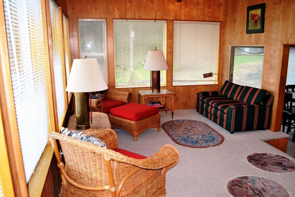 Entry sun room with spectacular ocean views, hide-a-bed couch and two wicker chairs.