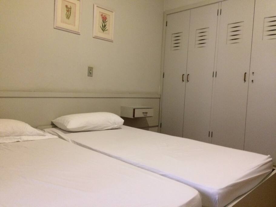 Quarto com duas camas de solteiro e um colchão. Com ar-condicionado