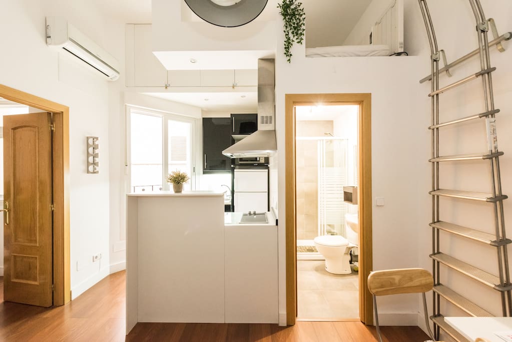 Vista desde el sofá a la cocina y la ventana al patio interno.
Pueden ver una escalera que da hacia una pequeña cama elevada . También puede utilizarse para guardar las maletas