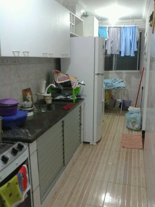 cozinha com fogão, geladeira, armarios, tanque e máquina de lavar.