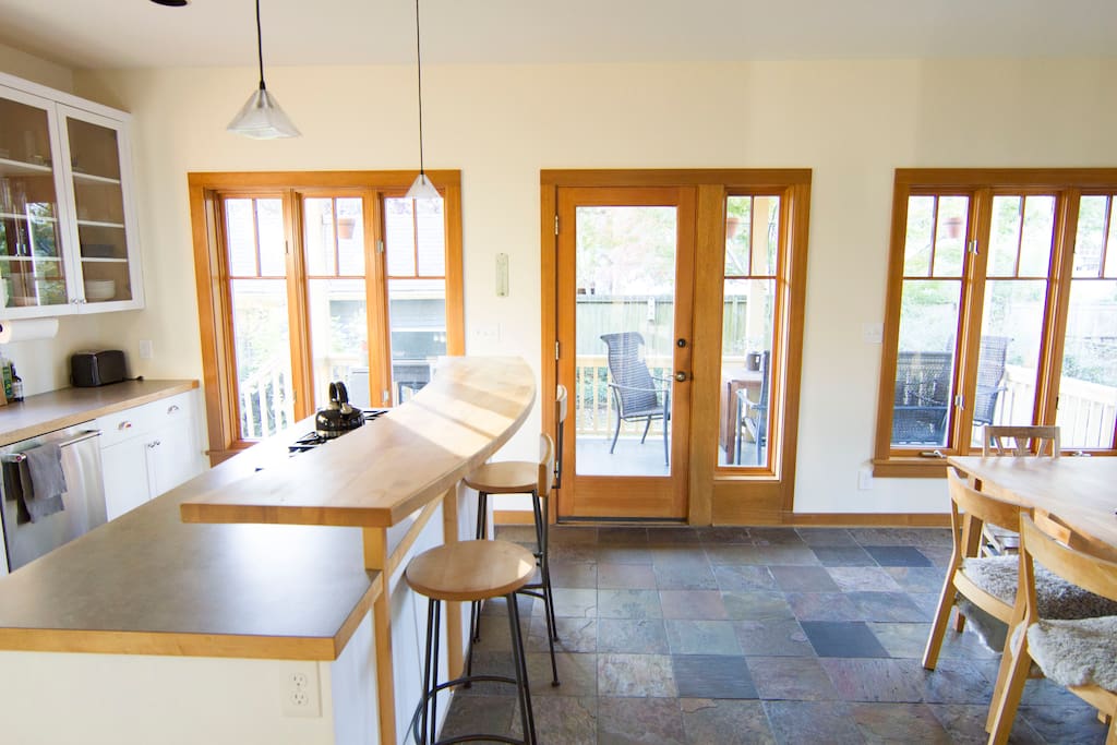 Open kitchen with walls of windows overlooking the dining area, with entry from the porch. Gas stove, dishwasher and coffee maker.