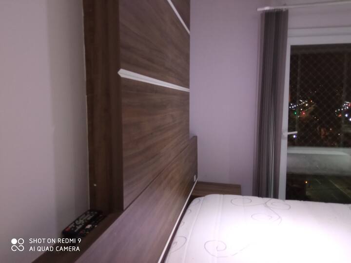 This is the entrance to the bedroom, where we see the headboard with the closet, part of the bed, and also part of the balcony window 