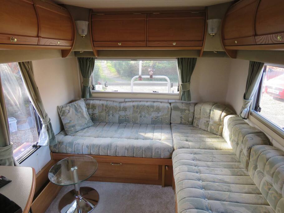 Spacious L shaped lounge area with a TV and windows on three sides all giving fine views.