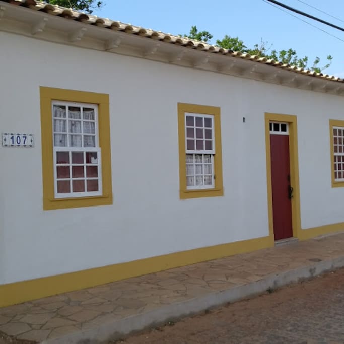 Nova fachada da casinha, com janelas de madeira, quihotinas e telhado