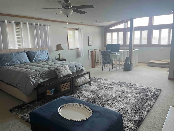 غرفة نوم ضخمة في الطابق الثاني مع سرير كينج وأريكة قابلة للسحب.  منطقة مكتب وأسرّة كلاب.  إطلالات على واجهة البحيرة والقناة.