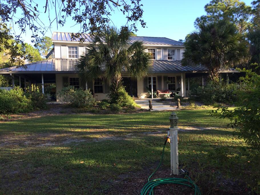 This is the front of the house there is seating and tables . It's a great spot for coffee or just hanging out. The road has a fence and garden border.