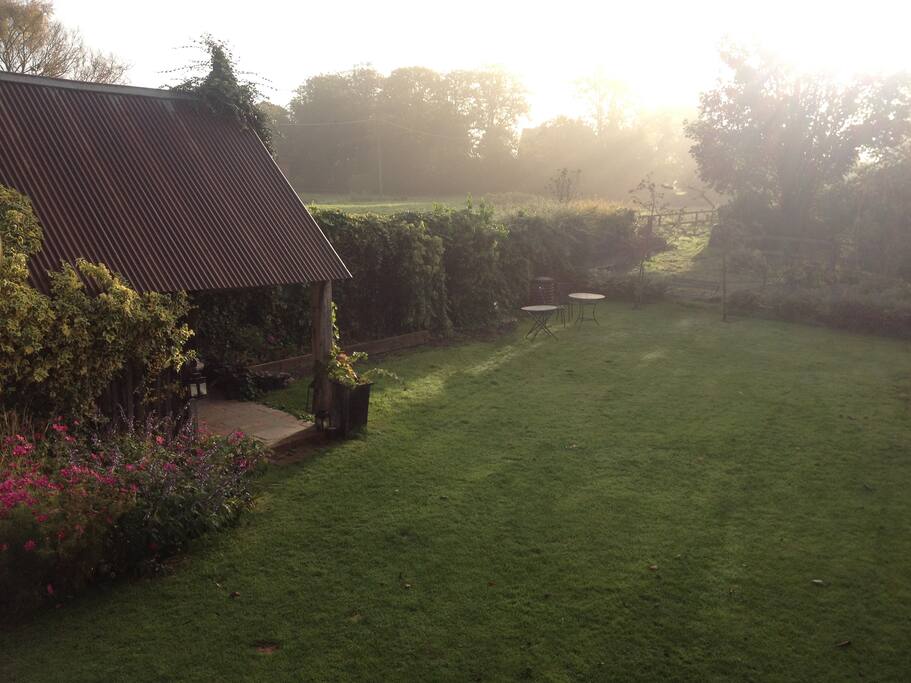 The garden early morning from the barn with a view over the field.