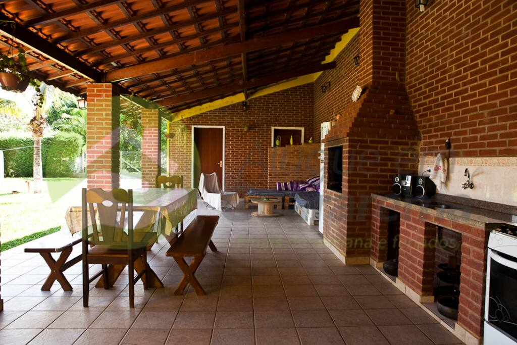 Área com cozinha mesa, sofá e churrasqueira.