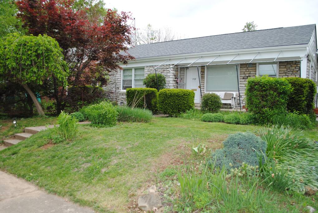 A private room in a field-stone house with flowers, shrubs, tall grasses and Japanese Maples.