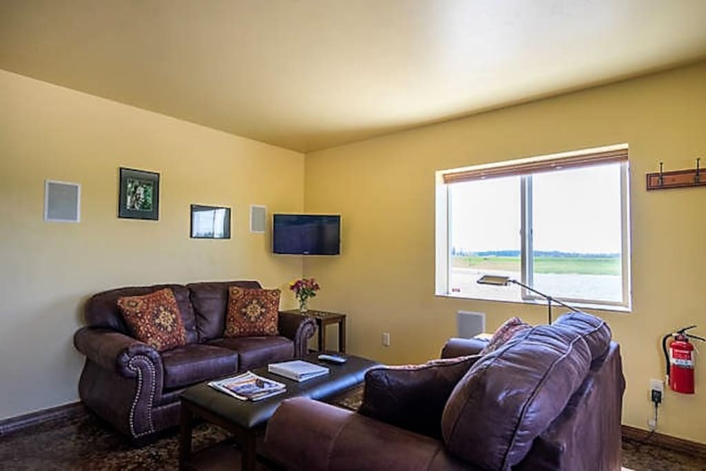 Comfortable living room with two love seats, a coffee table, two end tables, and a flat screen TV.