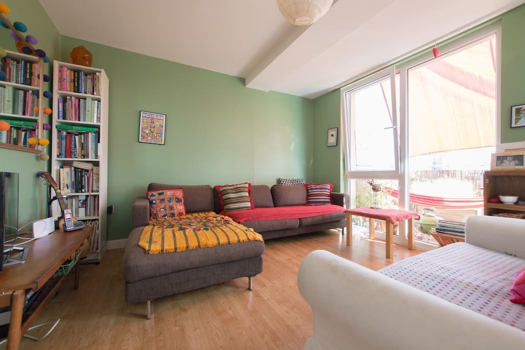 Living room area, comgortable sofas, television, big windows onto terrace, light.