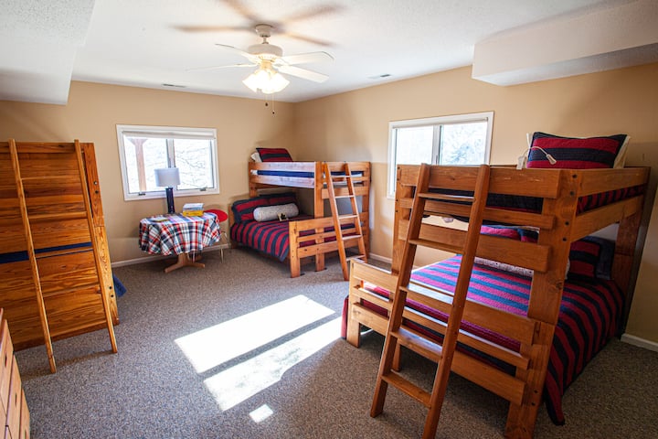 Expansive bunk room perfect for groups or families, featuring three bunk beds: two pyramid bunks (twin over double) and one twin bunk. Includes TV, a stereo, and a full private ensuite bathroom for ultimate convenience and comfort.