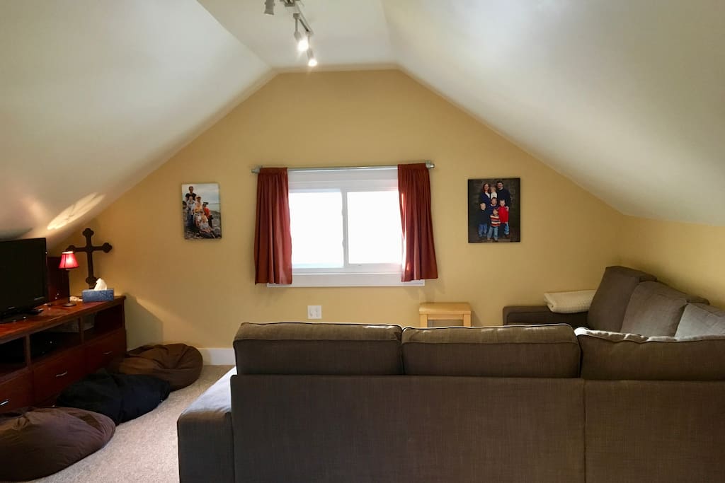 Fully finished attic with sectional seating and large screen TV.