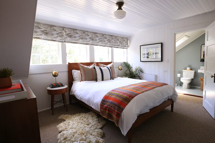 Bedroom No. 4 (third floor) faces the front yard and is always flooded with light! A queen bed with mid-century furnishings add to the home's 100+ year story. Decorative shades are black-out.