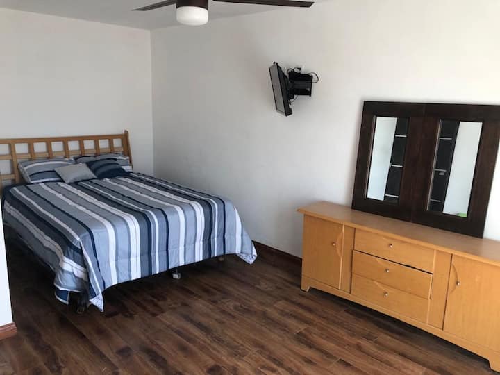 Chumba kilicho na kitanda cha ukubwa wa malkia, runinga, na  droo za nguo.