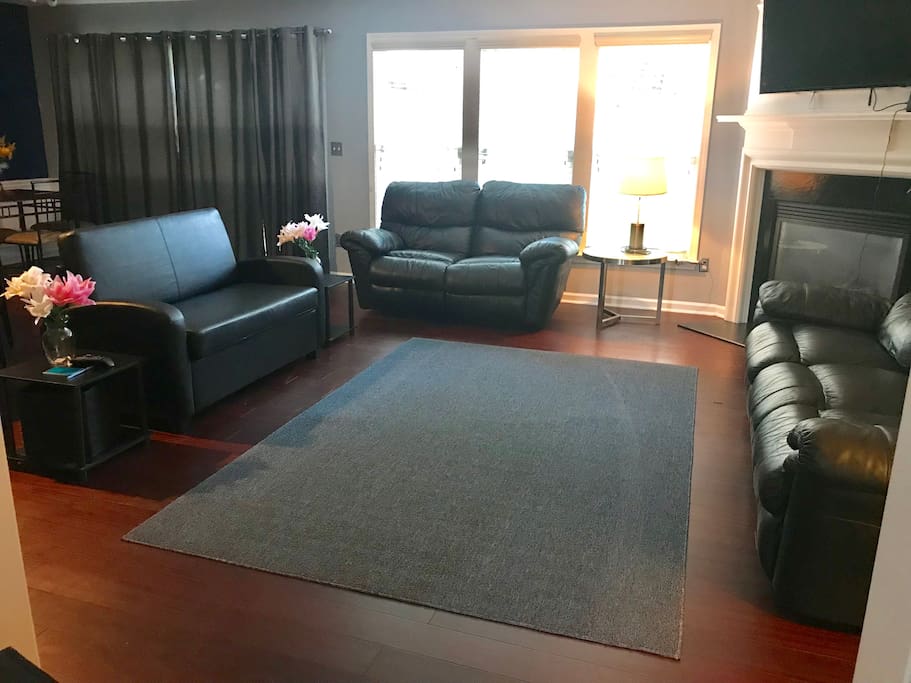 Living room hardwood floors & black leather furniture. One love seat is a twin pullout bed!