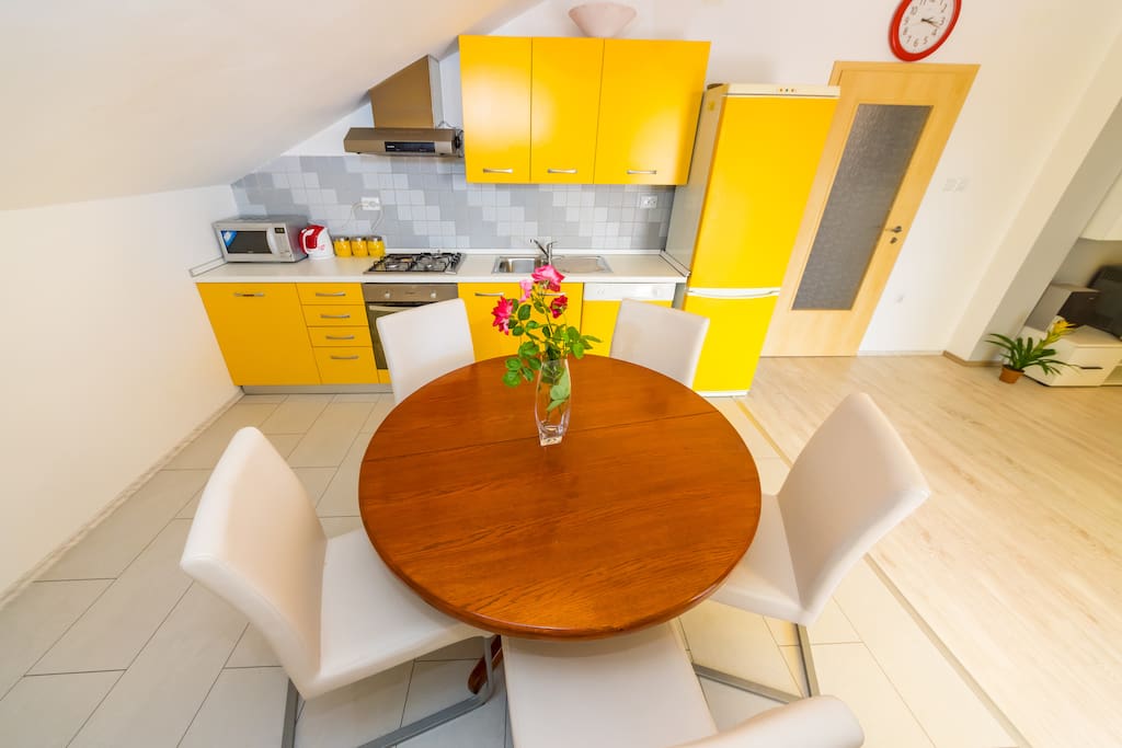 Dining room with kitchen: there is adjustable table (this is a smaller version), microwave, a kettle, electric oven, fridge, freezer, kitchen accessories and the dish washer