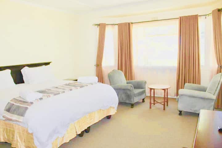 Main bedroom ensuite has king size bed, dressing table, wall tv, small fridge and built in wardrobes.  Also included are 2 wingback chairs and a small magazine table.