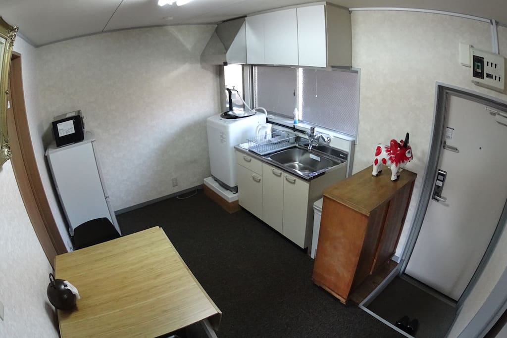 Kitchen with a microwave, a fridge, a kitcinette, and a laundry machine. A bamboo table is good for a small party.