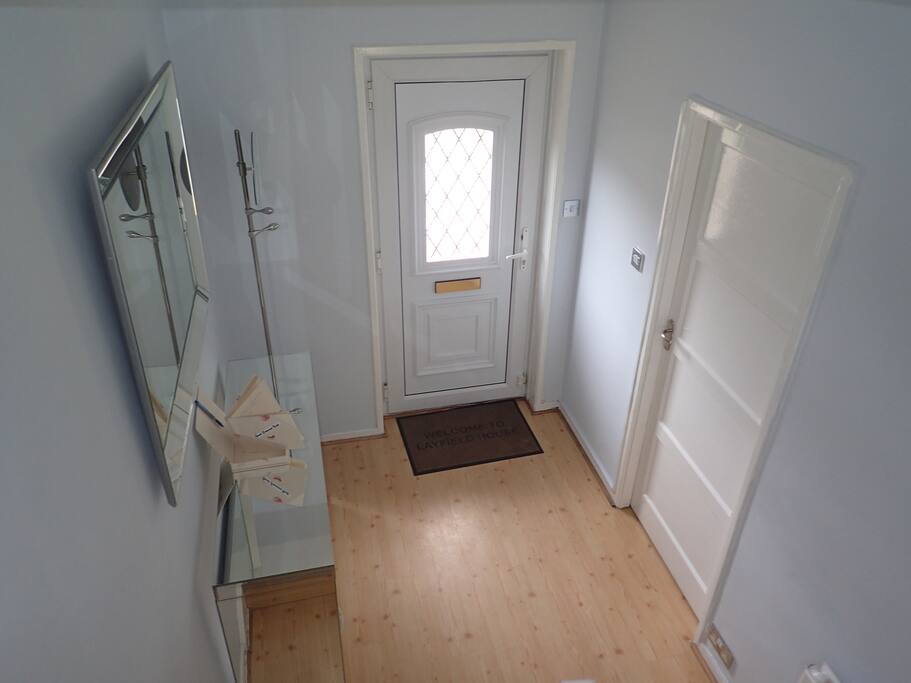 Brightly lit hallway with large vanity mirror, coat hanger & artwork