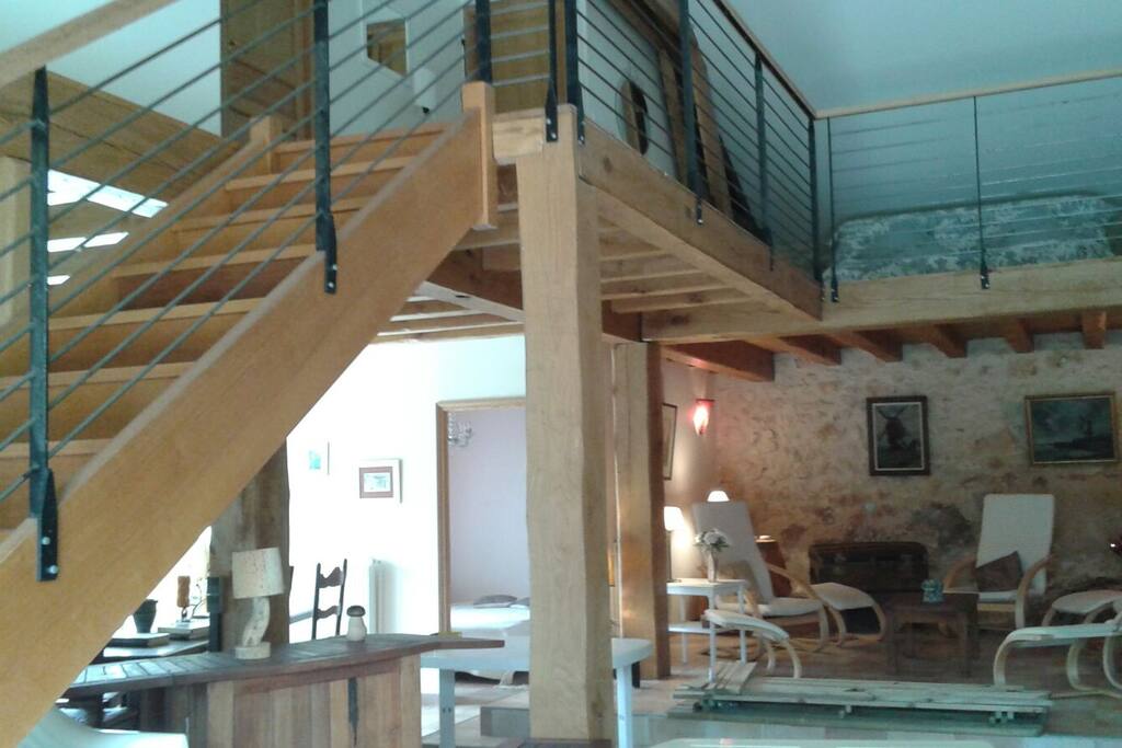 Immense cuisine ouverte, salon d'été et escalier donnant sur la mezzanine et les deux chambres du haut