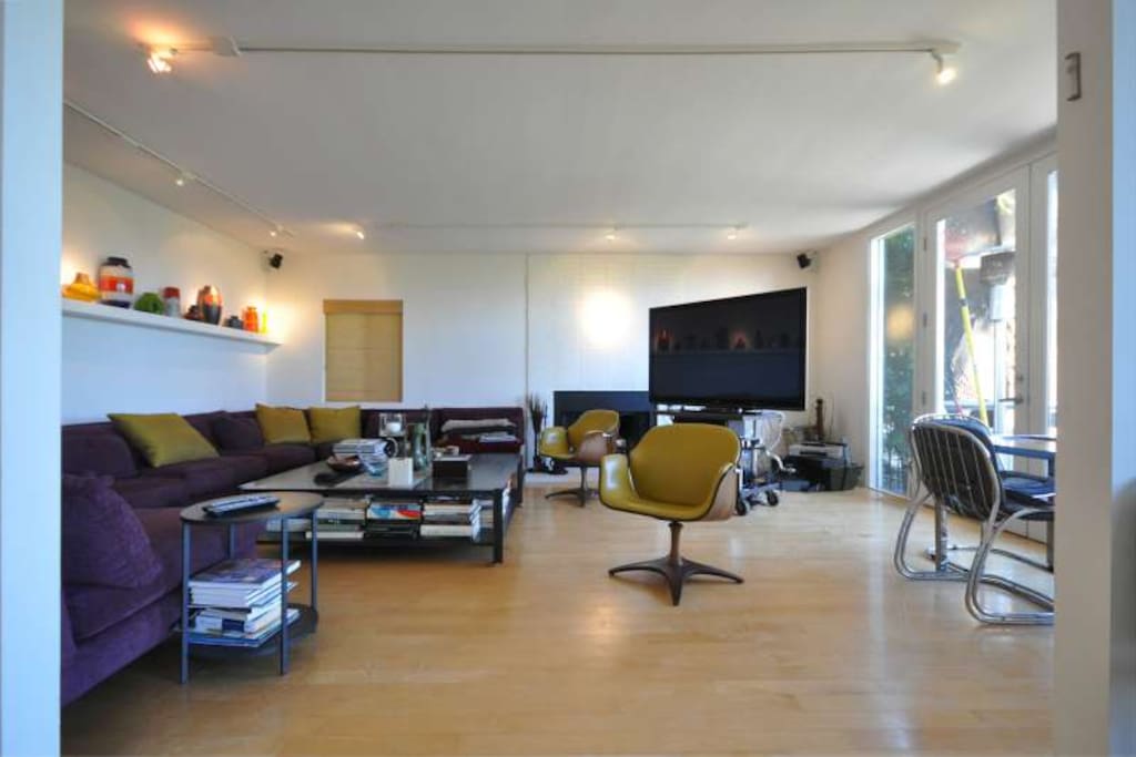 The living room houses a stunning sectional sofa, a gaming table and a 65" professional plasma TV.