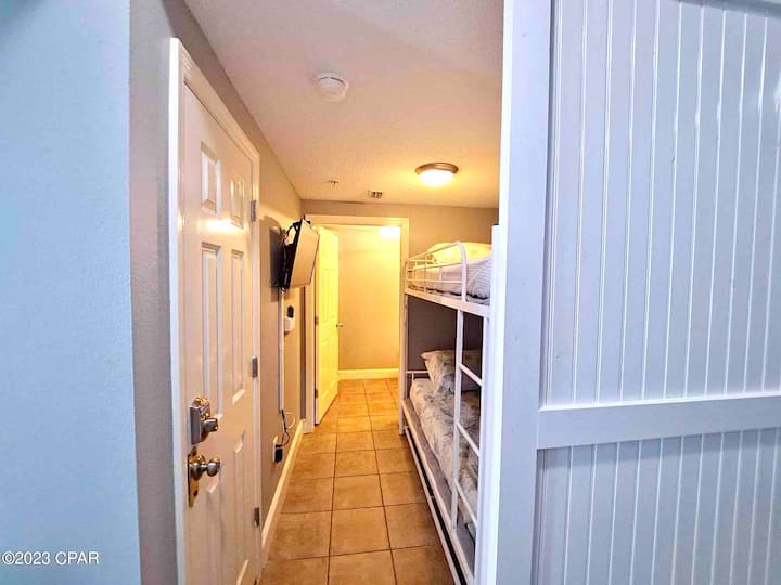 ทางเดินจากประตูทางเข้าห้องโถงเลื่อนผ่านเตียงสองชั้นและเข้าห้องน้ำ