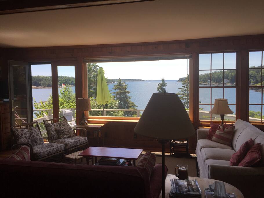 The great room opens up to a front and side porch, surrounded by water, a field, and stone steps to the dock and ocean life.