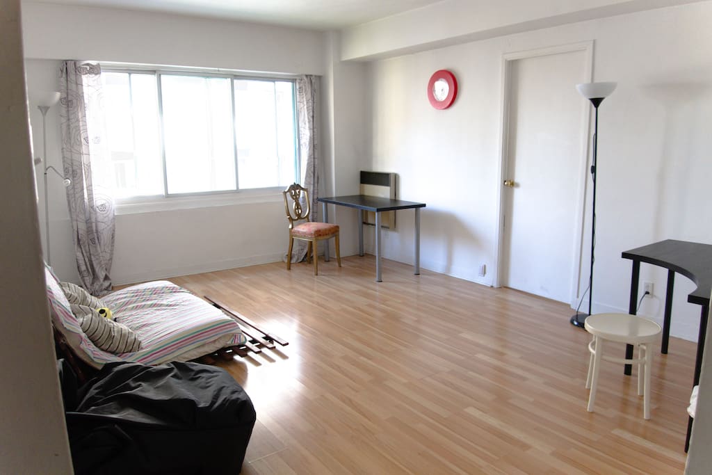 A large living area with 2 desks, a low couch, and a poof. That door you see leads to the bedroom