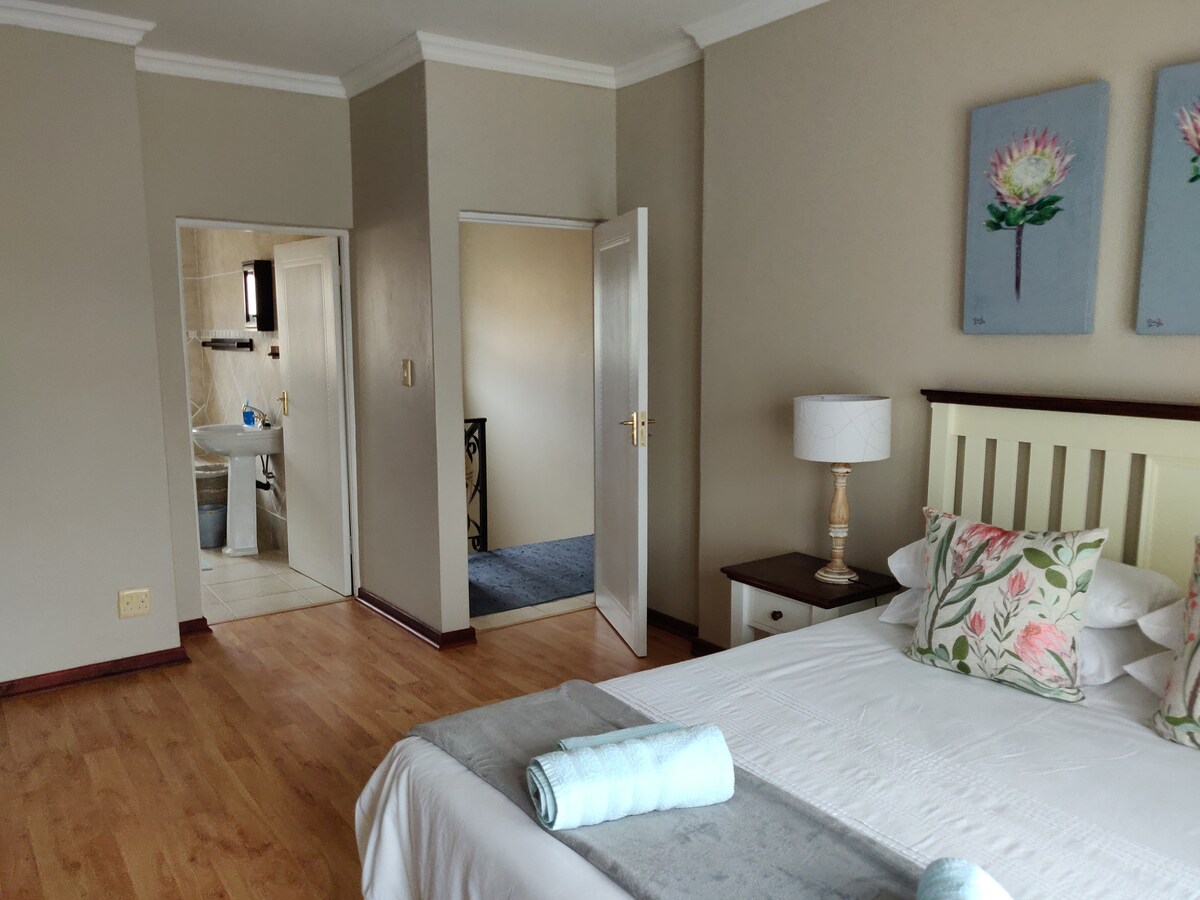 Dormitorio principal que consta de una cama doble y un baño privado con ducha y bañera. 