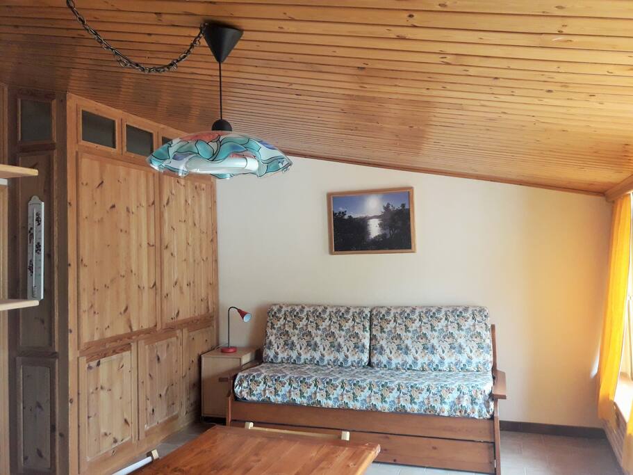 Soggiorno con soffitto imperlinato con divano letto (due letti singoli)