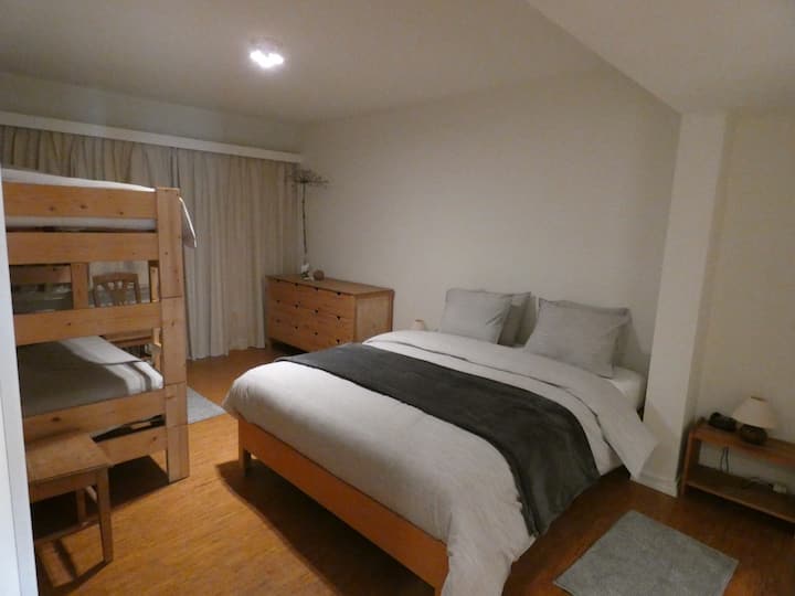 Dormitorio con cama matrimonial y litera con puerta a terraza estrecha. Y acceso a un baño grande con tina.