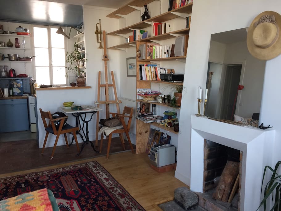 Cuisine américaine avec fenêtre, petite collection de livres, peintures et rétroprojecteur.