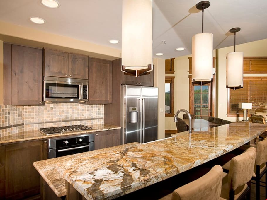 The fully-equipped kitchen features granite countertops, stainless steel appliances and a breakfast bar