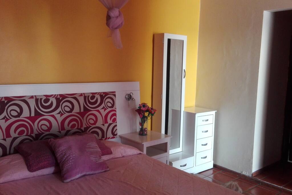 La habitación tiene instalado un velo de tul color rosa pálido arriba de la cama, para una mejor protección contra los mosquitos.
