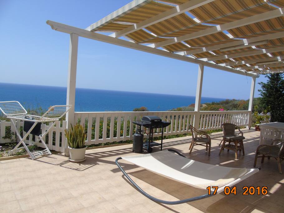 Terrazza sul mare arredata con sdraio, divano, tavolo sedie, barbecue.