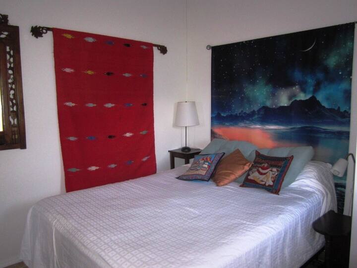 Bedroom with queen-sized bed. Room includes closet with shelves. 