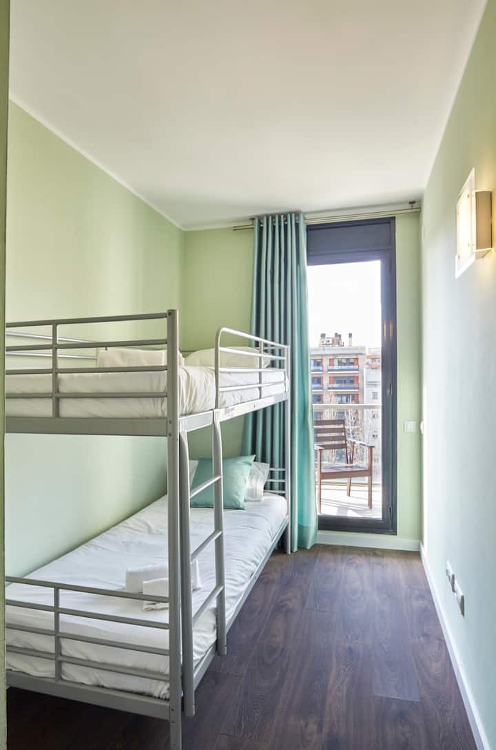 - Спална соба со кревети на спрат совршена за семејни или групни престои во градот  
- Прозорецот на балконот носи природна дневна светлина и надворешен поглед  
- Станот на Airbnb нуди удобност, приватност и флексибилност  

